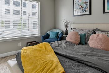a bedroom with a bed and a chair and a window at The Pointe at St. Joseph Apartments, South Bend, Indiana